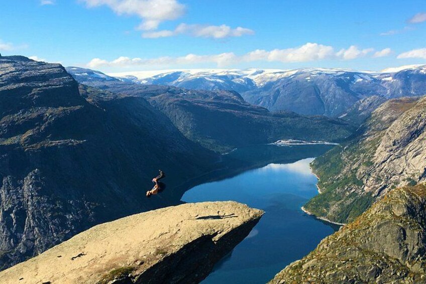 A person jumping off a cliff into a valley with a lake. 3