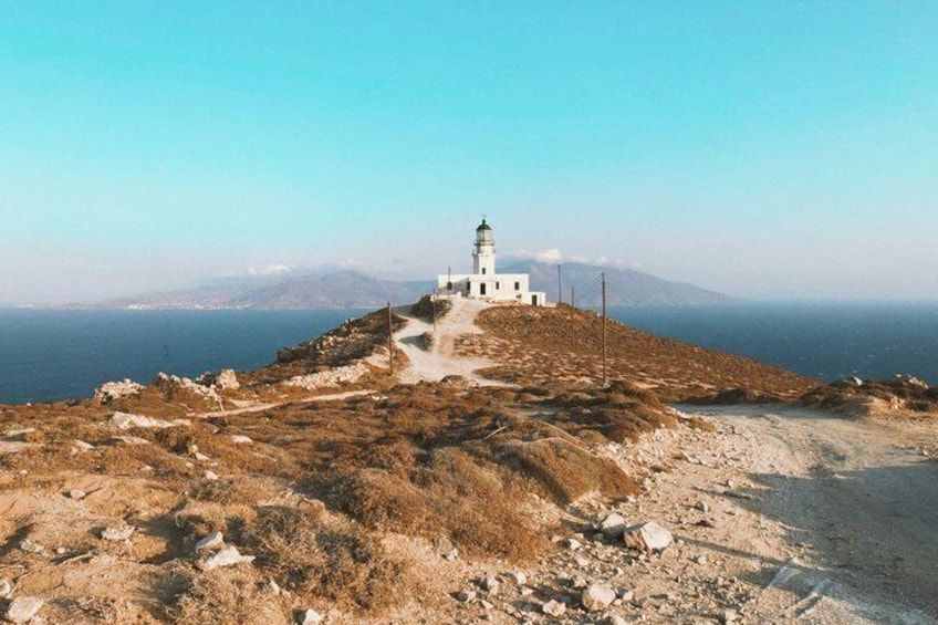 A white lighthouse on a rocky hill with a clear view of the sea and distant mountains. 3