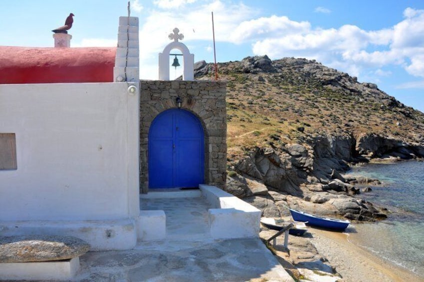 A coastal building with a blue door, a stone wall, and a rocky hillside in the background. 2