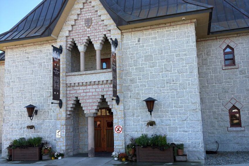 A stone building with a pointed roof, a wooden door, and two flower planters. 2