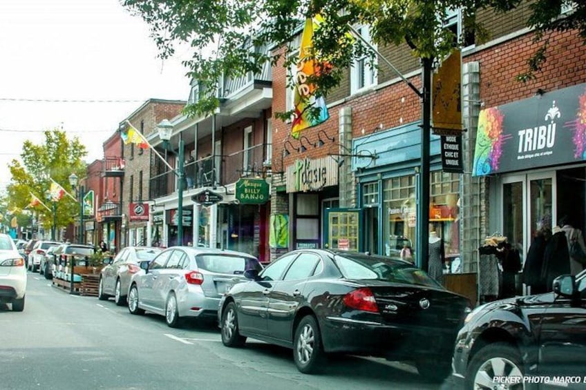A street lined with parked cars, storefronts, and a sign for Tribu. 3