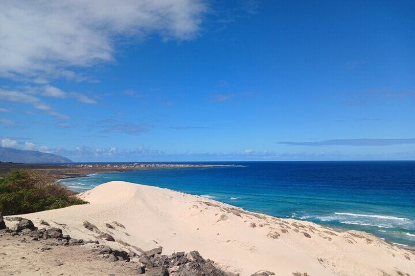 Paisaje costero con playa arenosa, océano y montañas a lo lejos. 5