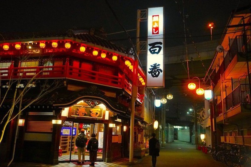 En traditionell japansk byggnad med en röd fasad och upplyst skyltning. 3
