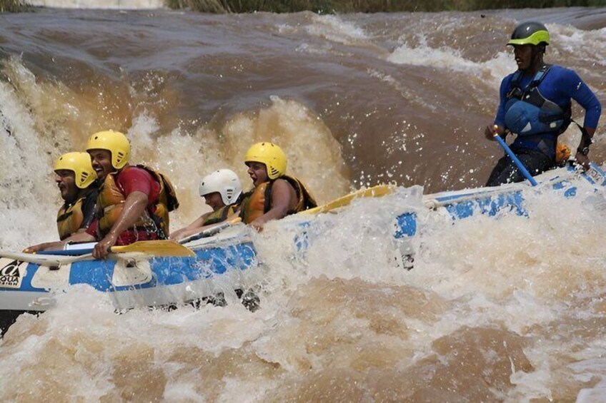 A group of people in a raft navigating through a turbulent river. 3
