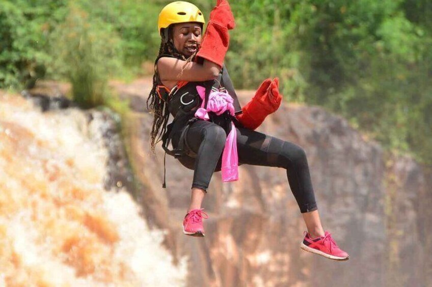 A person rappelling down a waterfall with a helmet and harness. 2