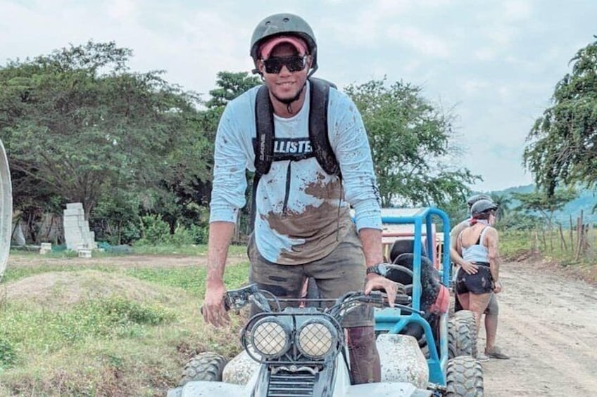 A person on a quad bike, another person in the background, and a vehicle. 3