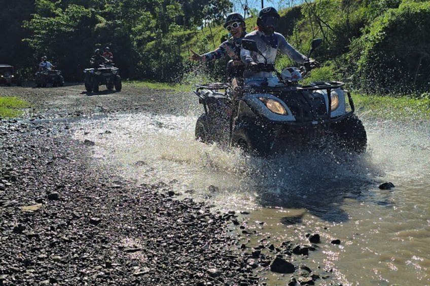An ATV crossing a shallow water body on a rocky path. 5