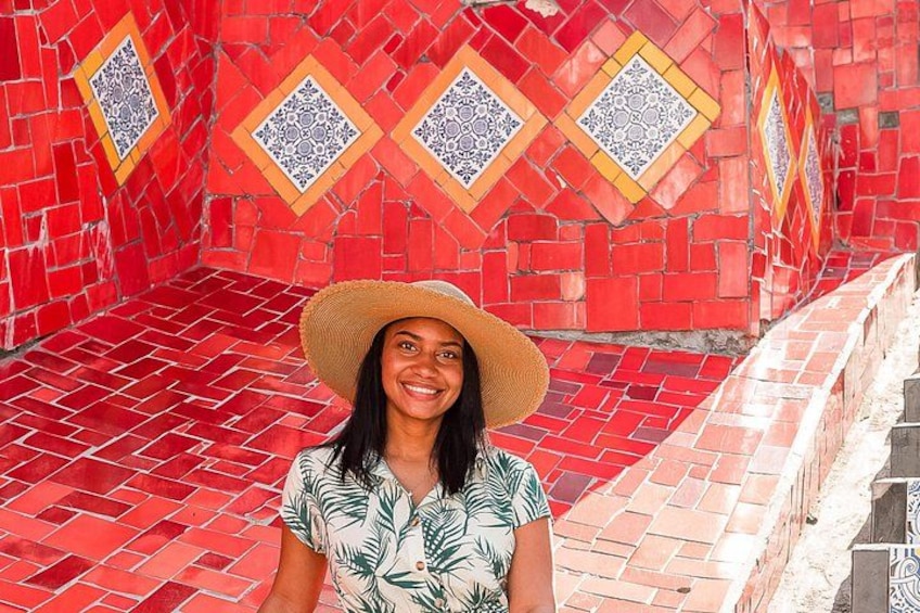Una persona in piedi di fronte a un muro di tegole rosse con motivi geometrici. 3