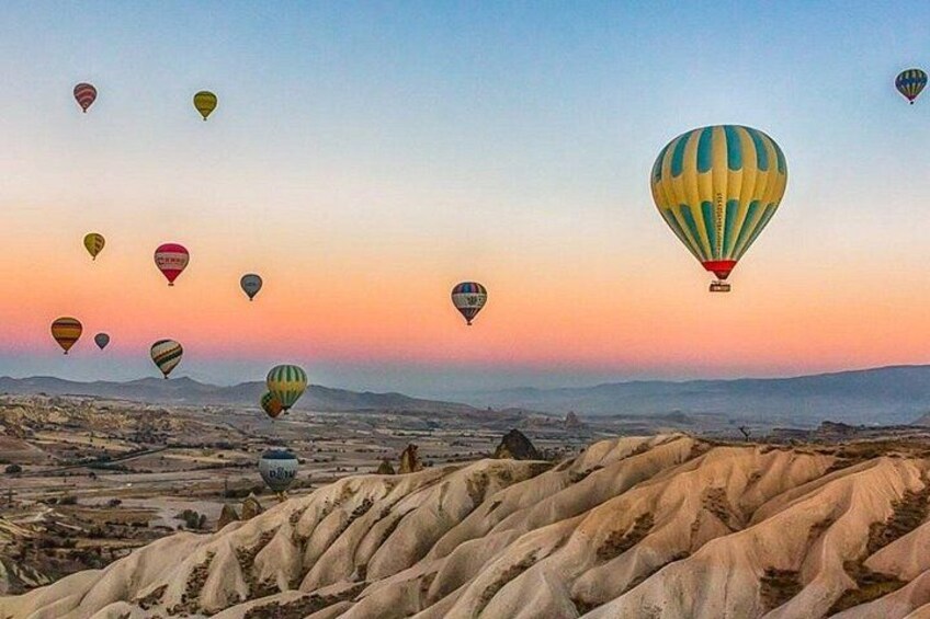 A landscape with hot air balloons, a desert terrain, and distant mountains. 1