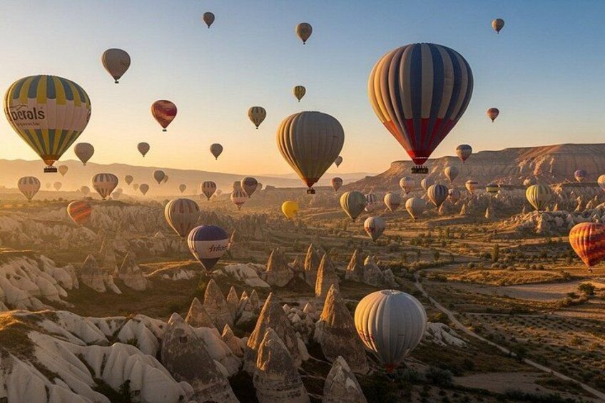 A landscape with numerous hot air balloons, rocky terrain, and a clear sky. 3