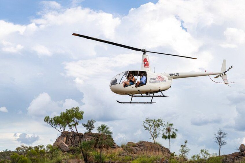 En helikopter flyver over et klippefyldt landskab med sparsom vegetation. 3