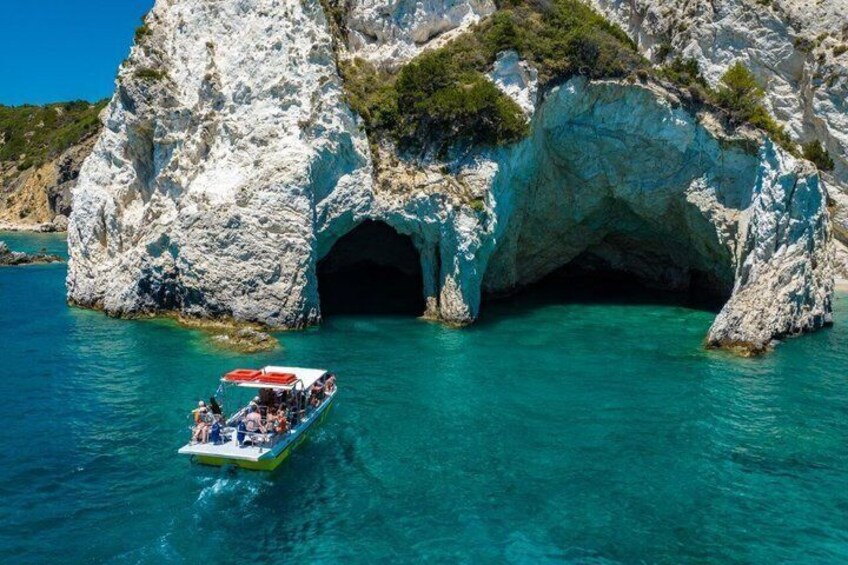 Una embarcación cerca de la entrada de una cueva rocosa, rodeada de aguas turquesas cristalinas. 2