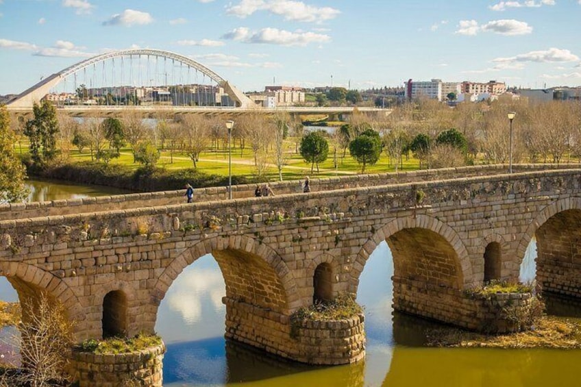 A stone bridge over a river with a modern bridge in the background. 2