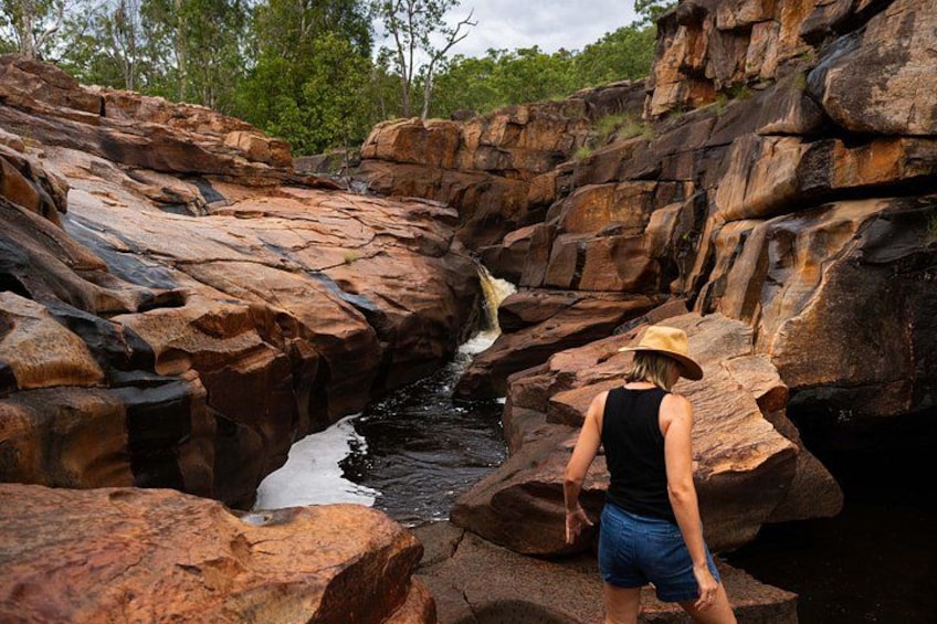 A person standing on rocks near a waterfall in a rocky landscape. 5
