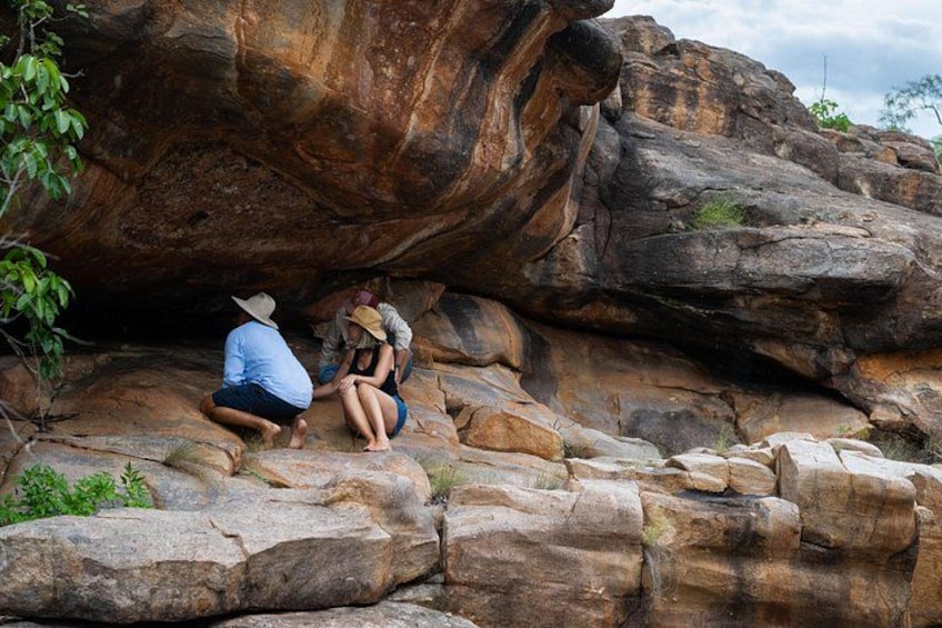 People sitting on rocks near a large boulder. 1