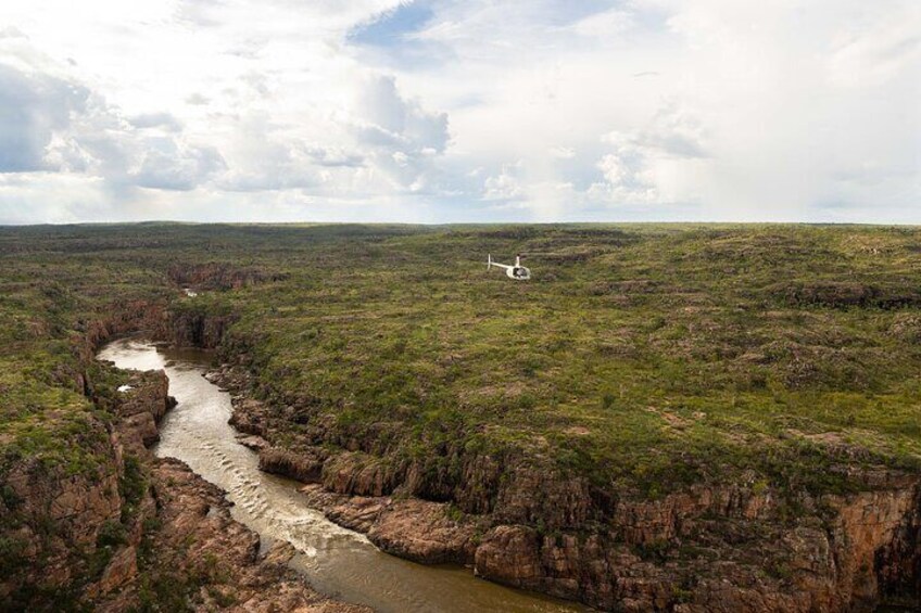 A river winding through a flat landscape with sparse vegetation and a white object in the distance. 5