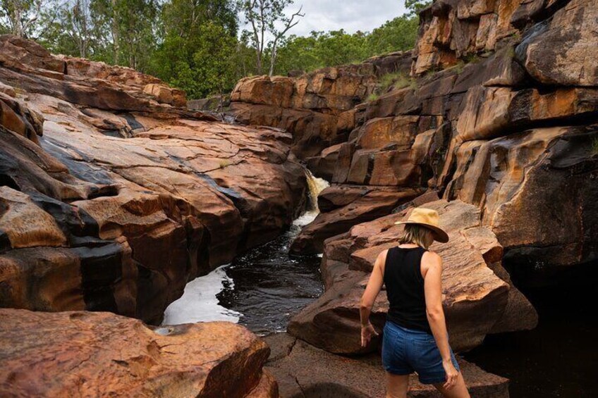 A person standing on rocks by a waterfall in a rocky canyon. 4