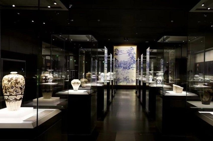 A museum exhibit with glass display cases containing ceramics and sculptures. 2