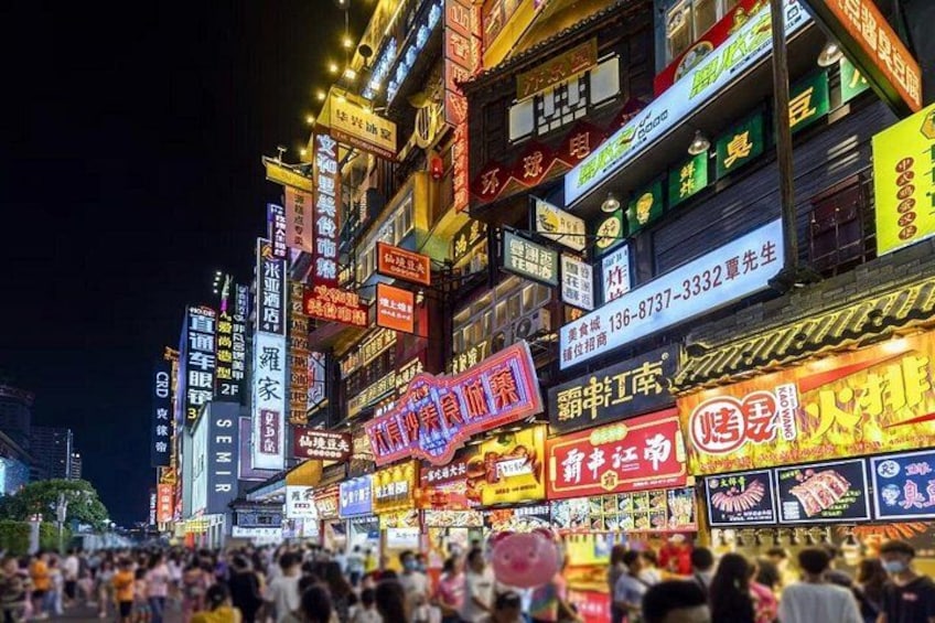 A busy street at night with illuminated signs and billboards. 3