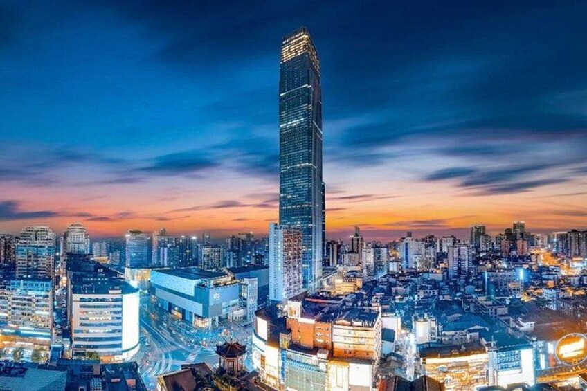 A cityscape at dusk with a prominent skyscraper, illuminated buildings, and a network of roads. 5