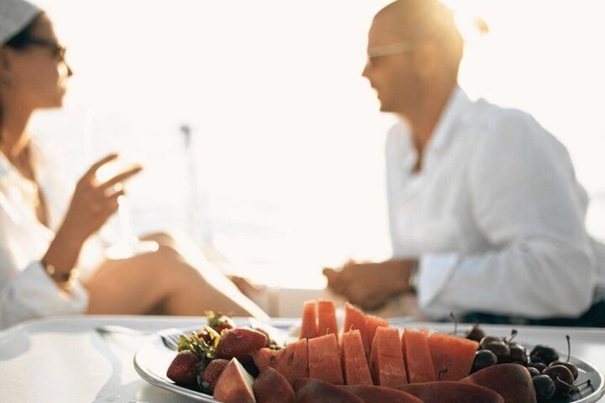 Two people sitting at a table with a plate of sliced salmon and berries. 2