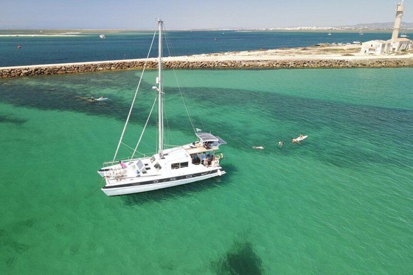 Un velero anclado cerca de un faro en aguas turquesas y cristalinas. 4