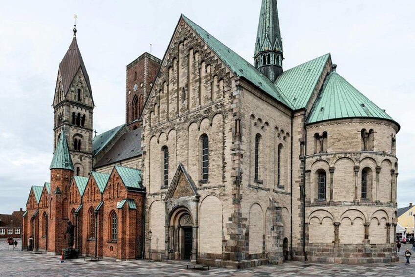 A historic church with a prominent tower and a large central building with a green roof. 3