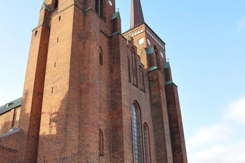 A tall brick church with a prominent spire and arched windows. 2