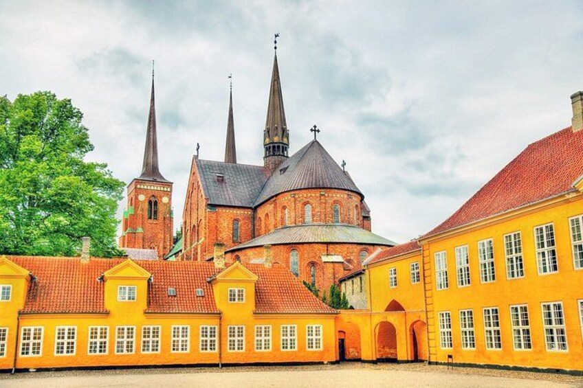 A historic church with three spires, surrounded by yellow buildings with red roofs. 5