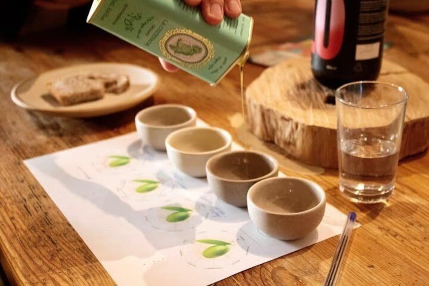 A person pouring a liquid into five small cups on a wooden table. 1
