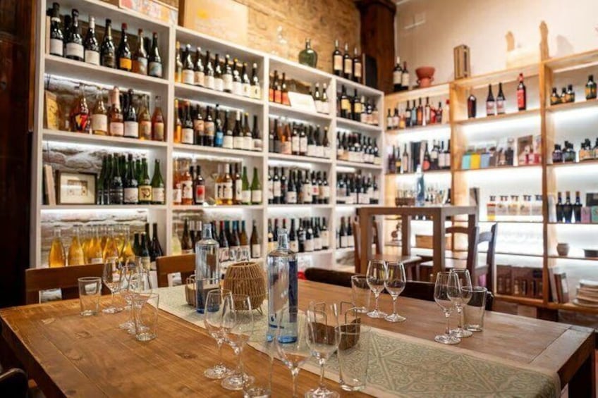 A wine cellar with shelves of bottles and glasses on a wooden table. 3