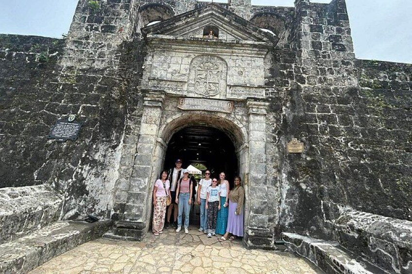 Un arco de piedra histórico con un grupo de personas de pie frente a él. 4