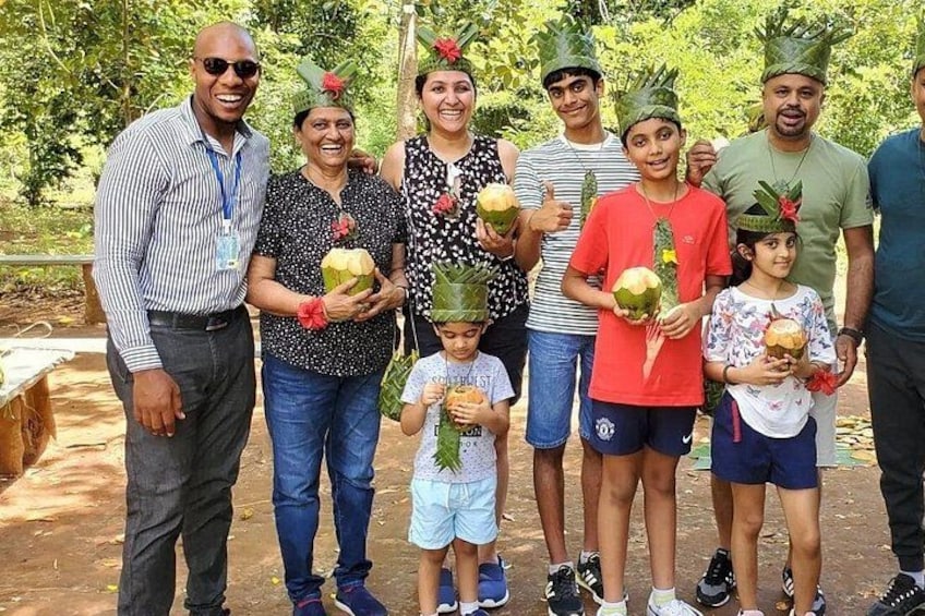 Un grupo de personas al aire libre, algunas sosteniendo cocos, con vegetación al fondo. 4