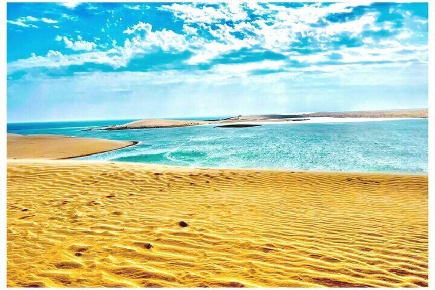 A desert landscape with sand dunes and a body of water. 2