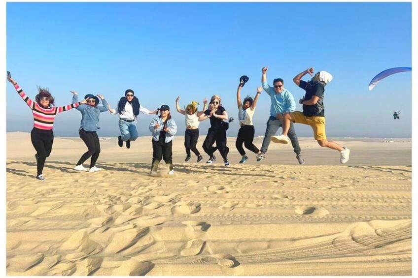 Un grupo de personas saltando en la arena de una playa. 2