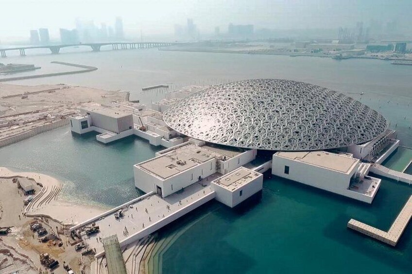 A large, circular building with a unique pattern, surrounded by water and connected to the mainland by bridges. 2