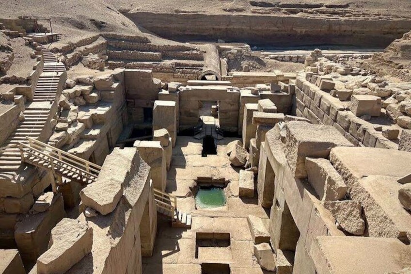 Ruinas de piedra antiguas con un canal central de agua y una escalera que conduce a un nivel superior. 1