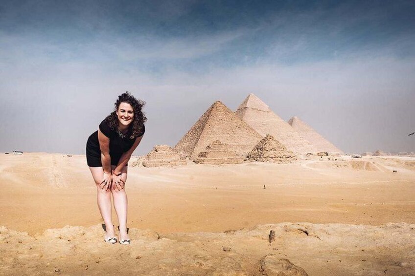 A person standing in a desert with pyramids in the background. 3