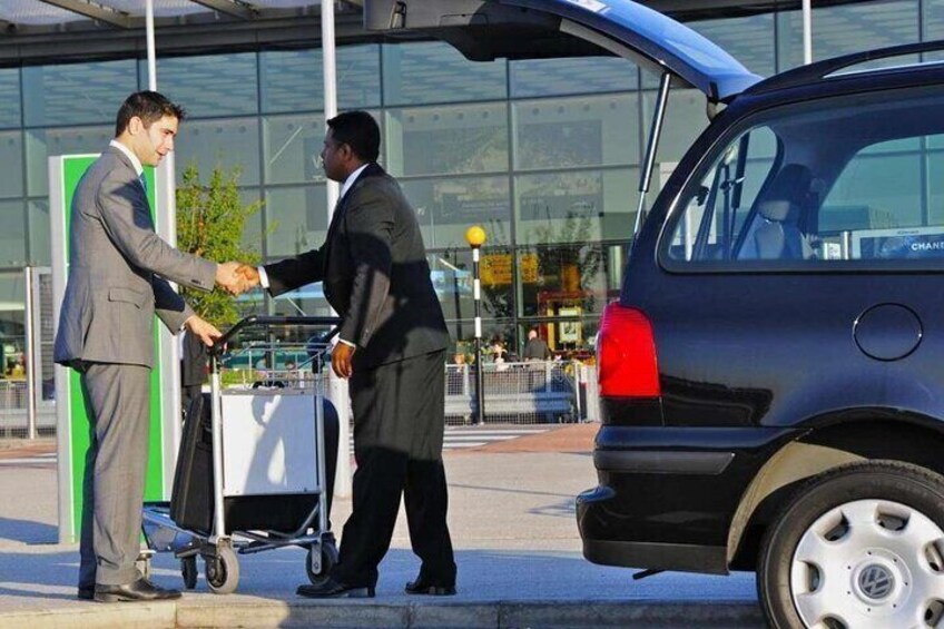 Two men shaking hands in front of a car and a building. 1