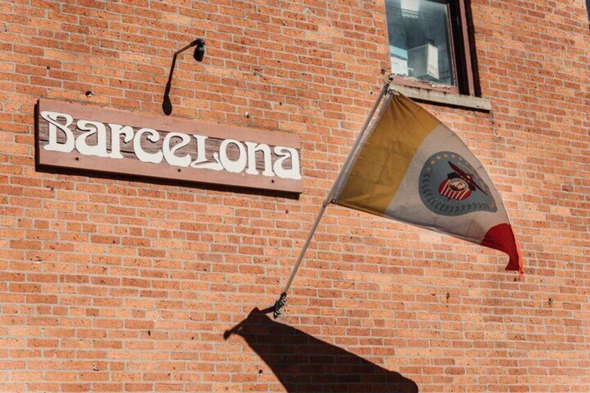 A brick building with a sign that reads "Barcelona" and a flag with a logo. 4