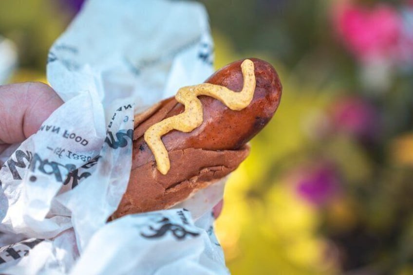 A hot dog with mustard being held by a person. 3