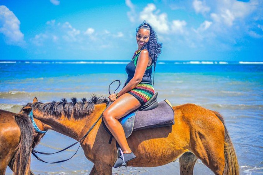 Eine Person reitet auf einem Pferd am Strand, im Hintergrund das Meer. 4