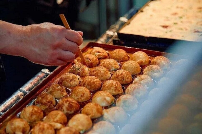 A person cooking round, golden-brown food items in a pan. 2