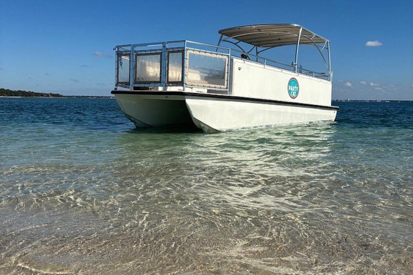 A boat named 'PATTY' anchored in clear shallow waters with a clear sky in the background. 2