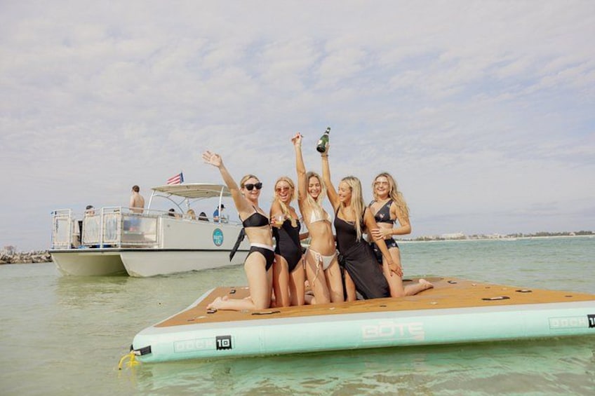 A group of people on a small boat, a larger boat in the background, and calm water. 4