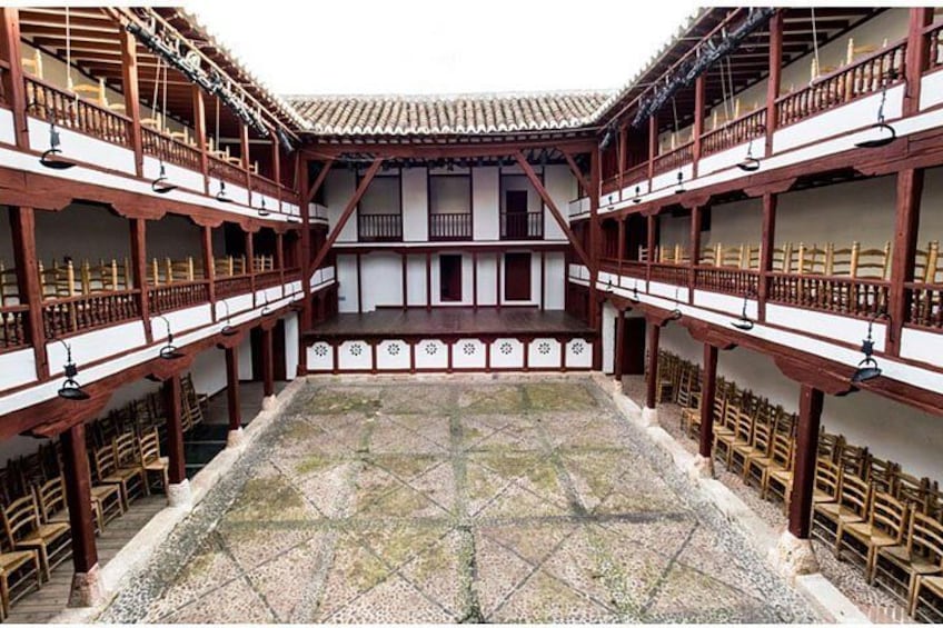 A traditional courtyard with wooden balconies, tiled flooring, and chairs arranged for seating. 4