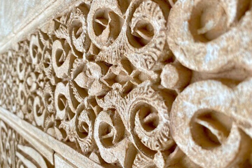 Ein Detailaufnahme einer kunstvollen Steinschnitzarbeit mit verschlungenen Spiralmustern und floralen Ornamenten. 3