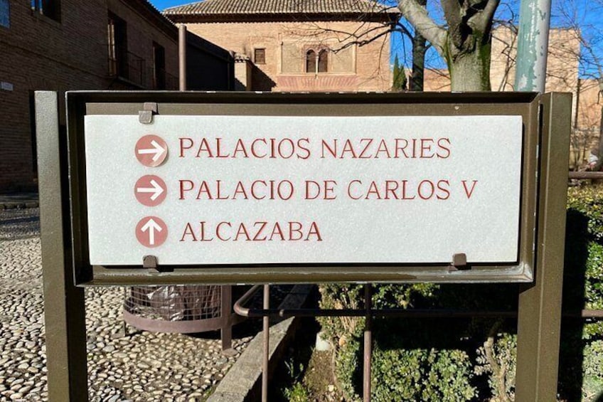 A sign with directions to Palacio de Carlos V and Palacio de los Nazarios. 4