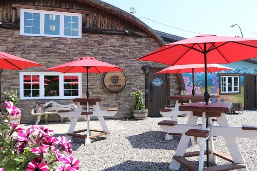 Ein rustikales Steinhaus mit Picknicktischen und roten Sonnenschirmen. 2