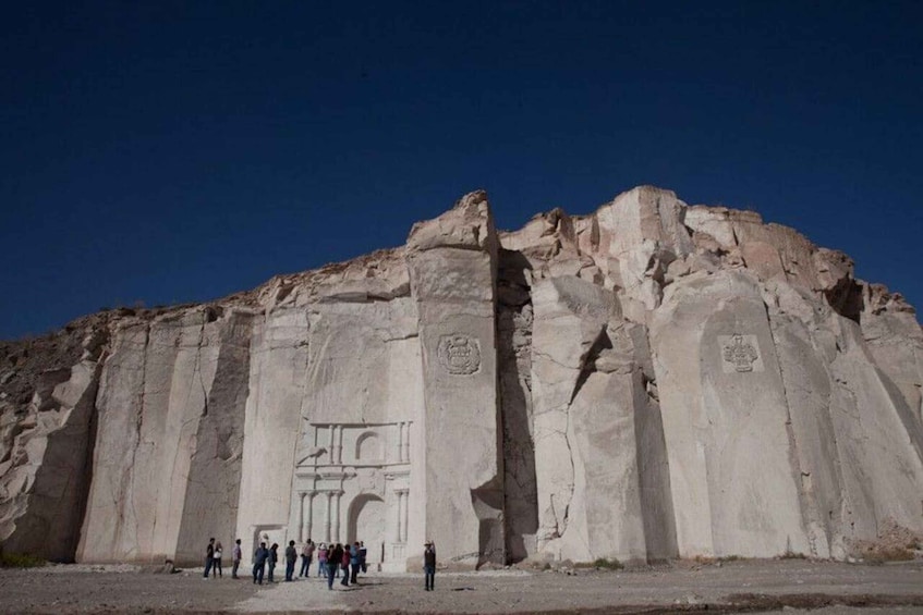 A large rock formation with carved columns and a central archway. 5